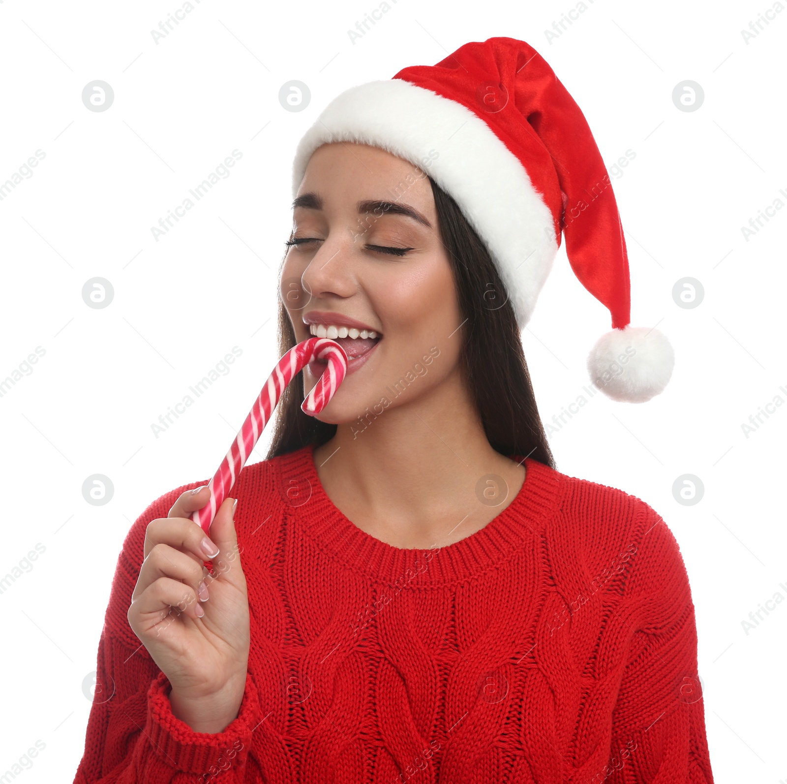 Photo of Young woman in red sweater and Santa hat holding candy cane on white background. Celebrating Christmas