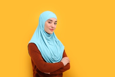 Photo of Portrait of Muslim woman in hijab on orange background, space for text