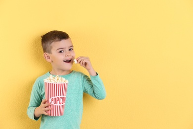 Cute little boy with popcorn on color background. Space for text