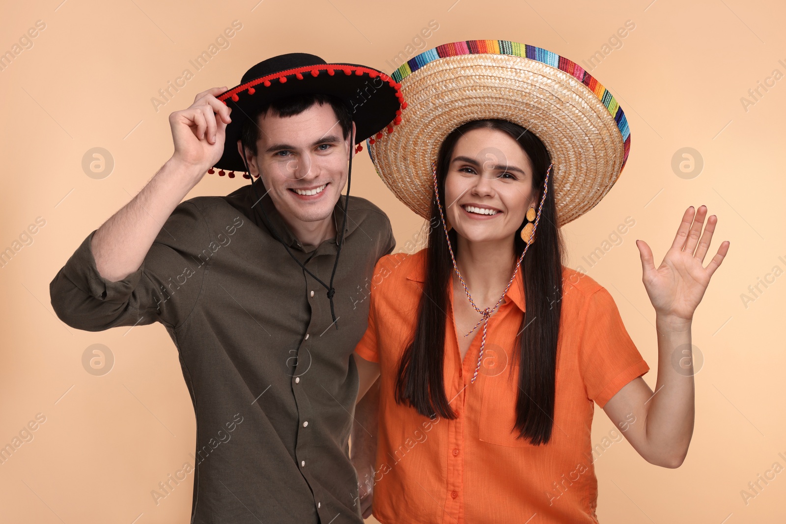 Photo of Lovely couple woman in Mexican sombrero hats on beige background