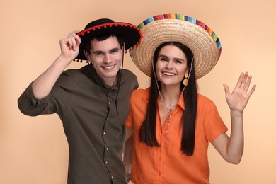 Lovely couple woman in Mexican sombrero hats on beige background