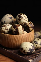 Photo of Bowl and many speckled quail eggs on table, closeup