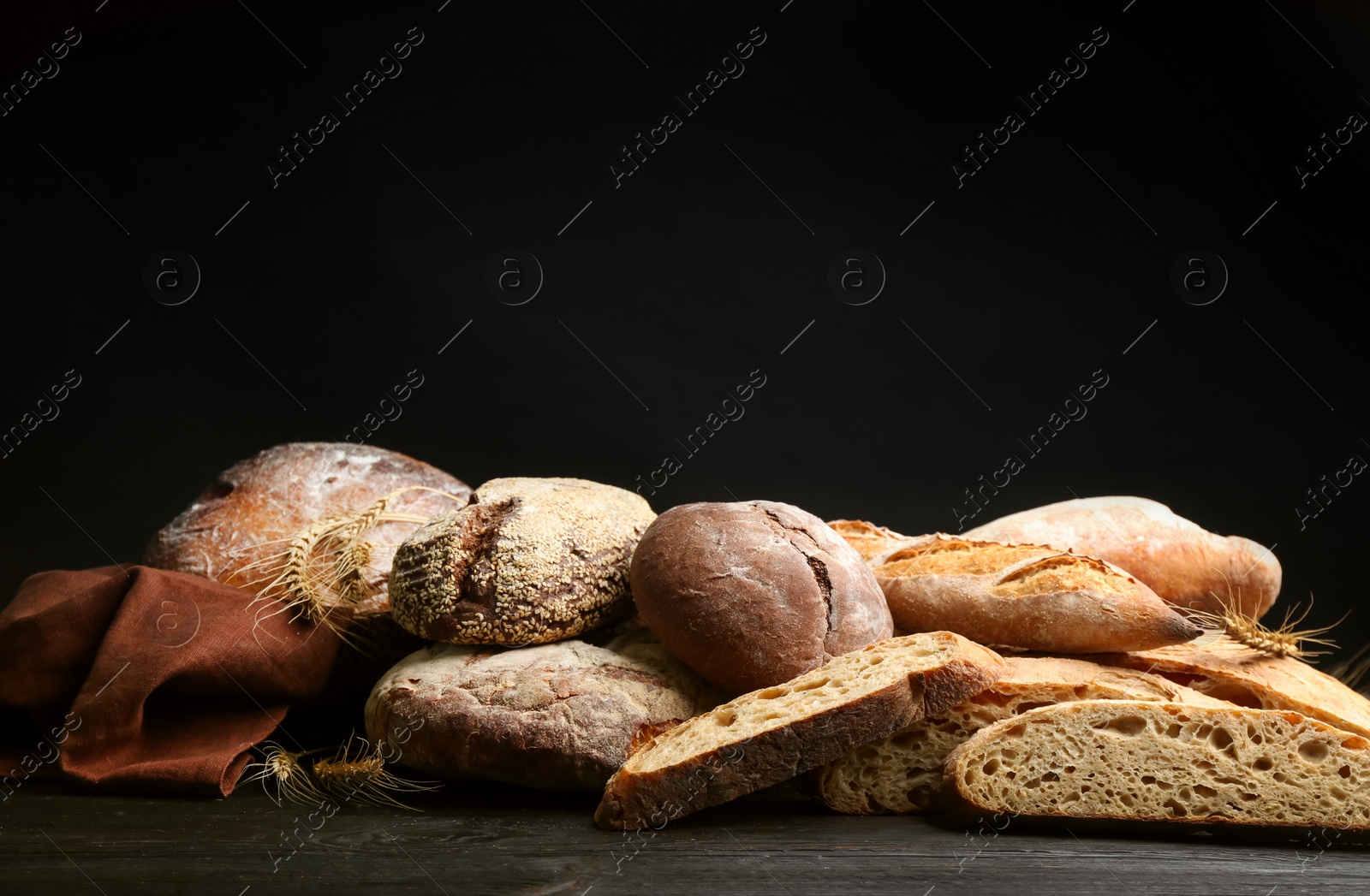 Photo of Different kinds of fresh bread on black wooden table