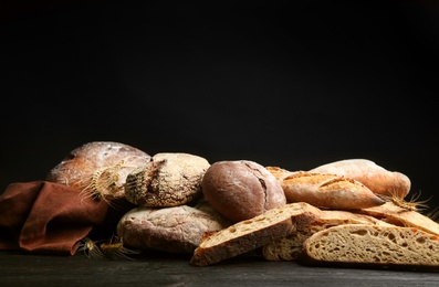 Photo of Different kinds of fresh bread on black wooden table