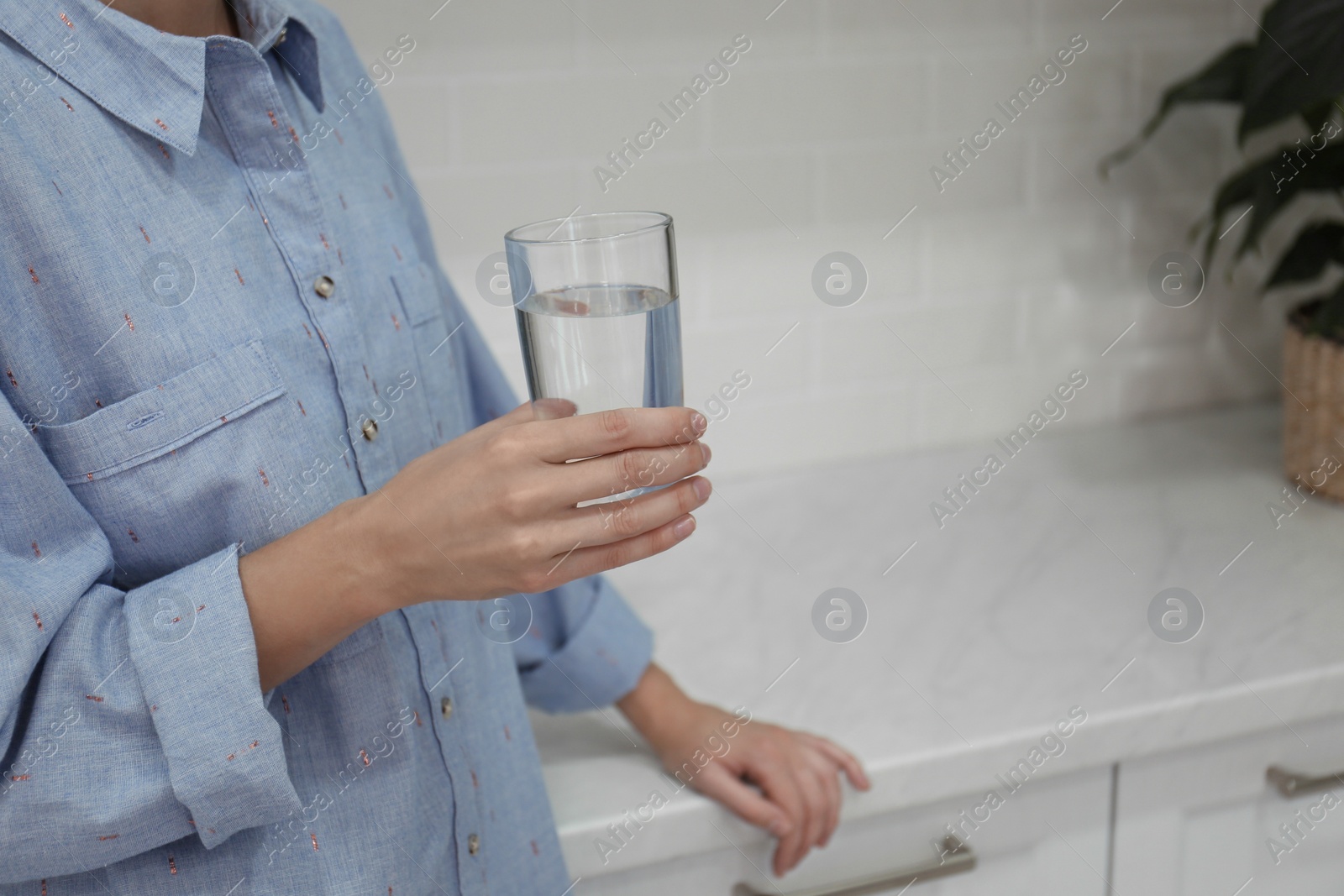 Photo of Woman holding glass of water at home, closeup