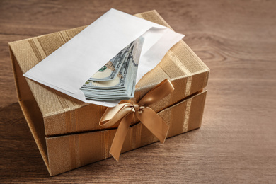 Photo of Gift box with dollar bills on wooden table