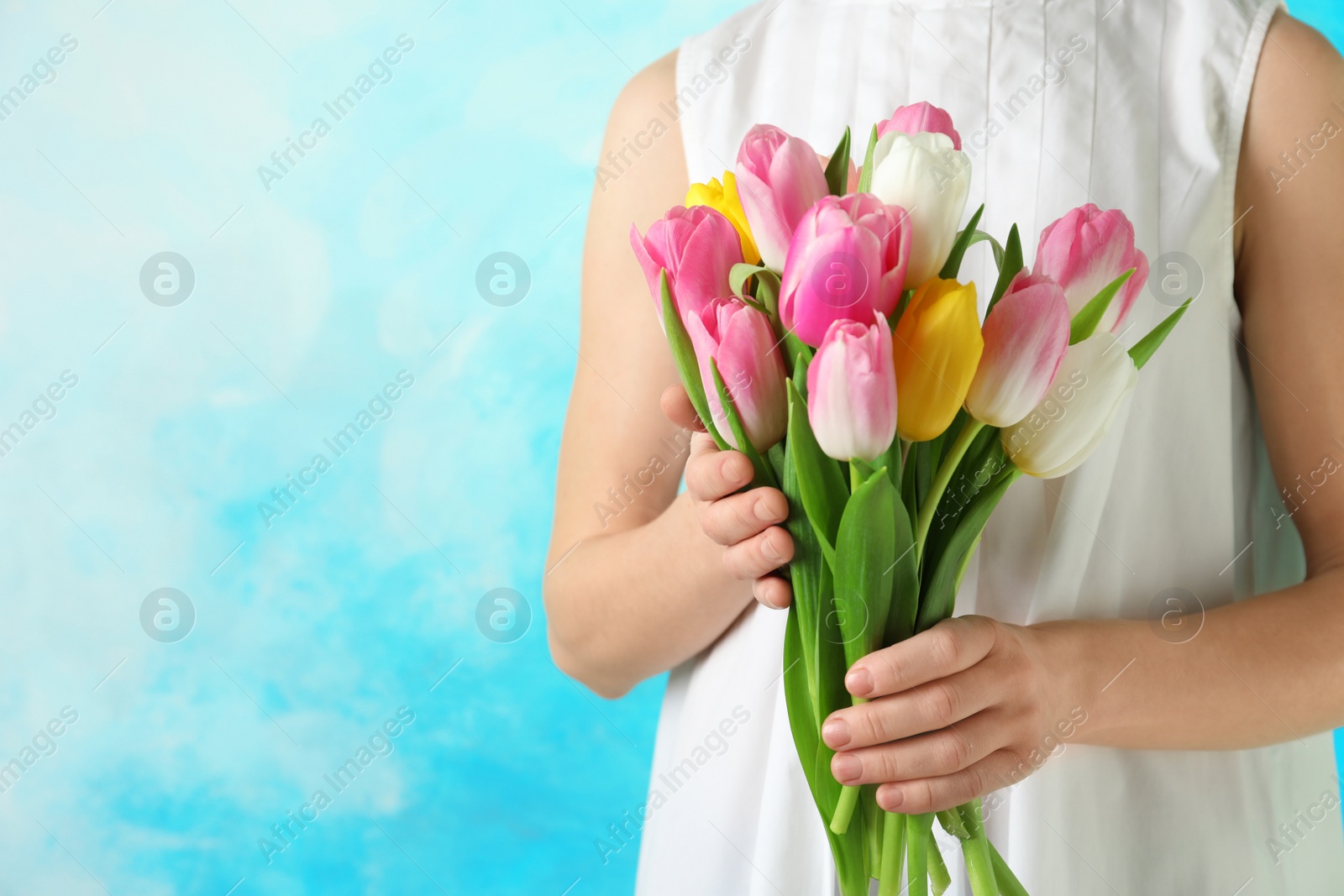 Photo of Girl holding bouquet of beautiful spring tulips on color background, closeup with space for text. International Women's Day