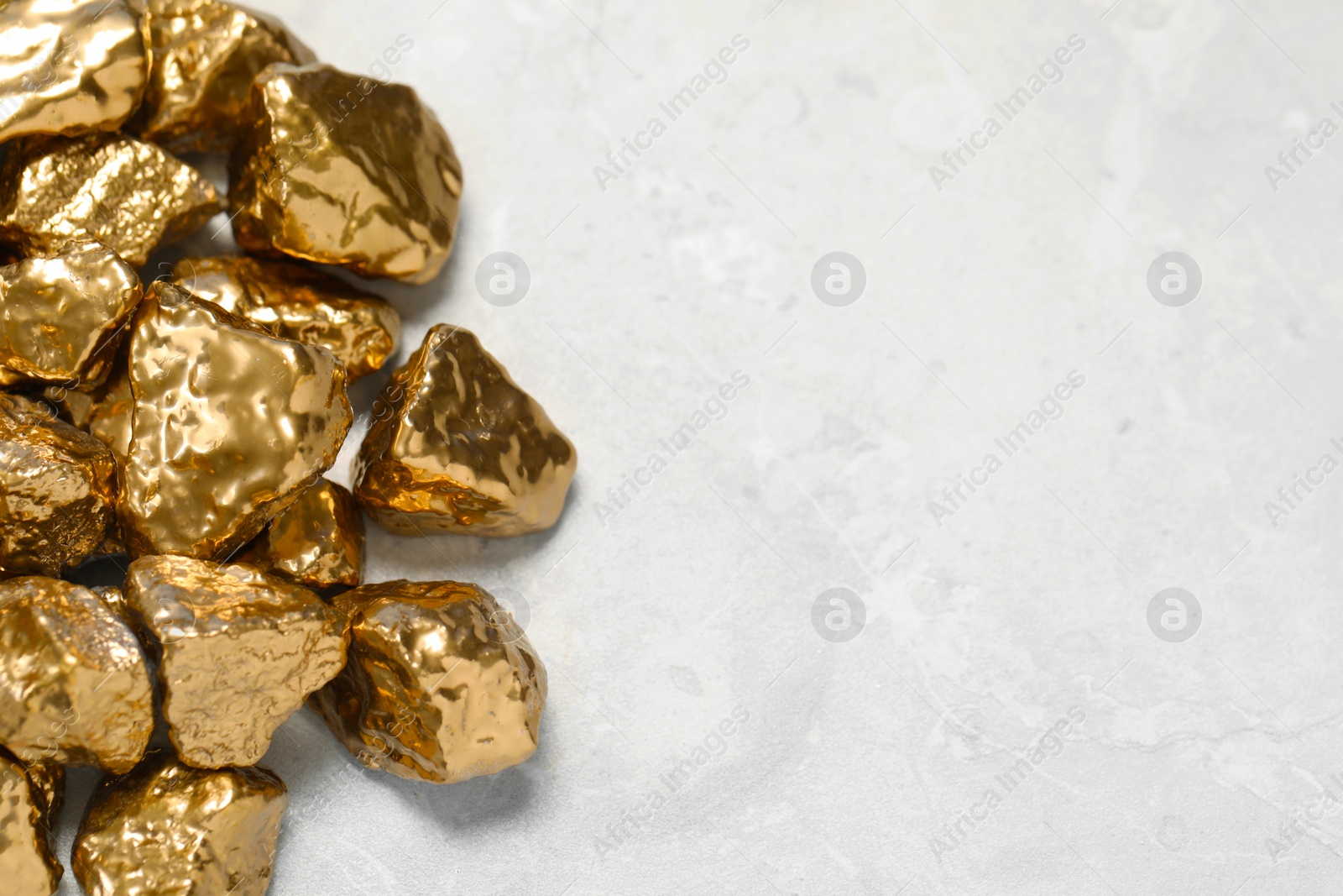 Photo of Pile of gold nuggets on light grey marble table, flat lay. Space for text