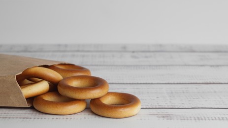Photo of Bag with tasty dry bagels (sushki) on white wooden table, closeup. Space for text