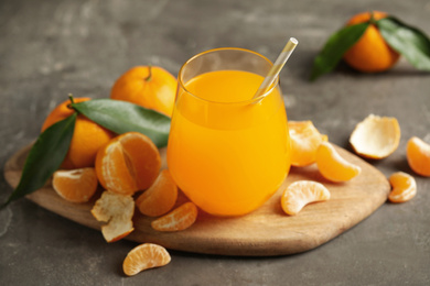 Photo of Fresh tangerines and glass of juice on grey table