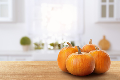 Image of Fresh pumpkins on wooden table in kitchen. Space for text