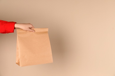 Woman holding paper bag on color background. Mockup for design