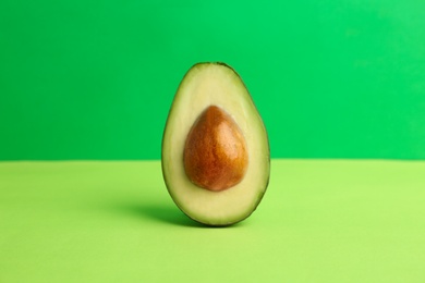 Photo of Half of ripe avocado on color background