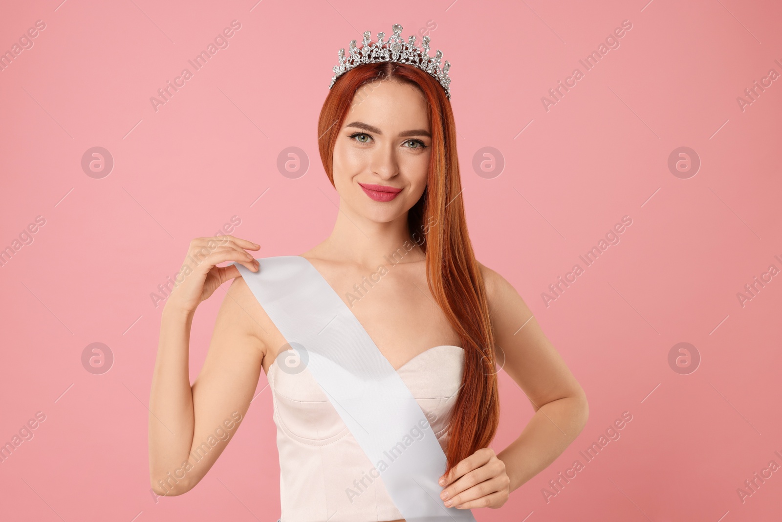 Photo of Beautiful young woman with tiara and ribbon on pink background