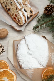 Photo of Wrapped Christmas Stollen with decoration on wooden table, flat lay