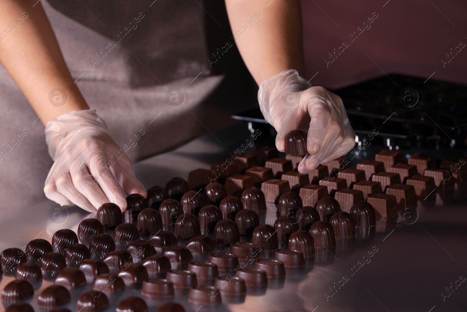Photo of Woman with delicious candies at production line, closeup