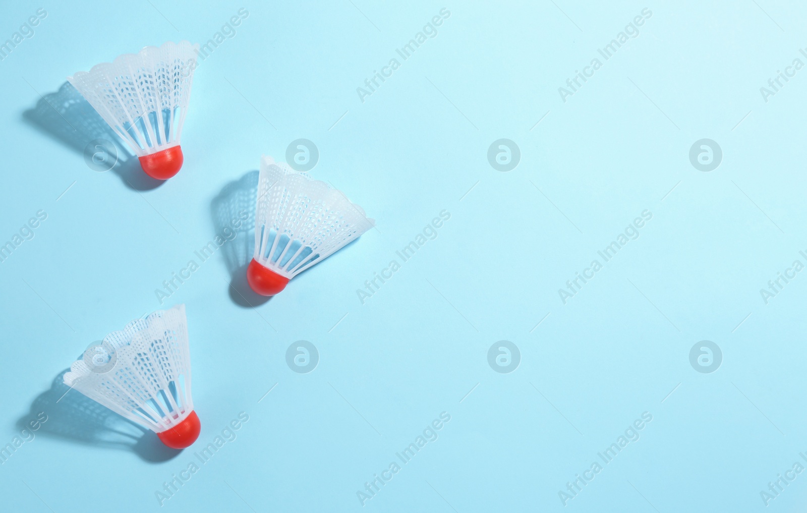 Photo of Badminton shuttlecocks on light blue background, flat lay. Space for text