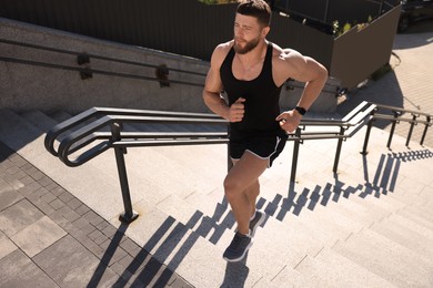 Photo of Man running up stairs outdoors on sunny day