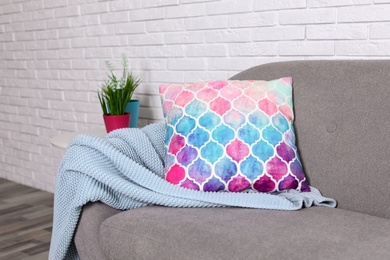 Cozy sofa with pillow and plaid near brick wall. Idea for living room interior design