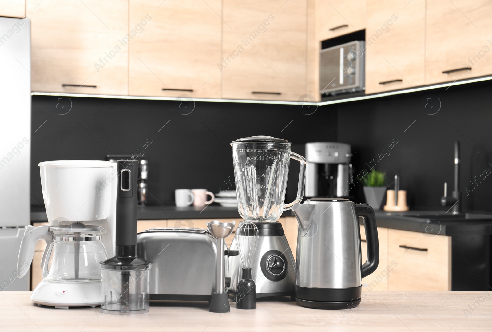 Photo of Modern domestic appliances on wooden table in kitchen