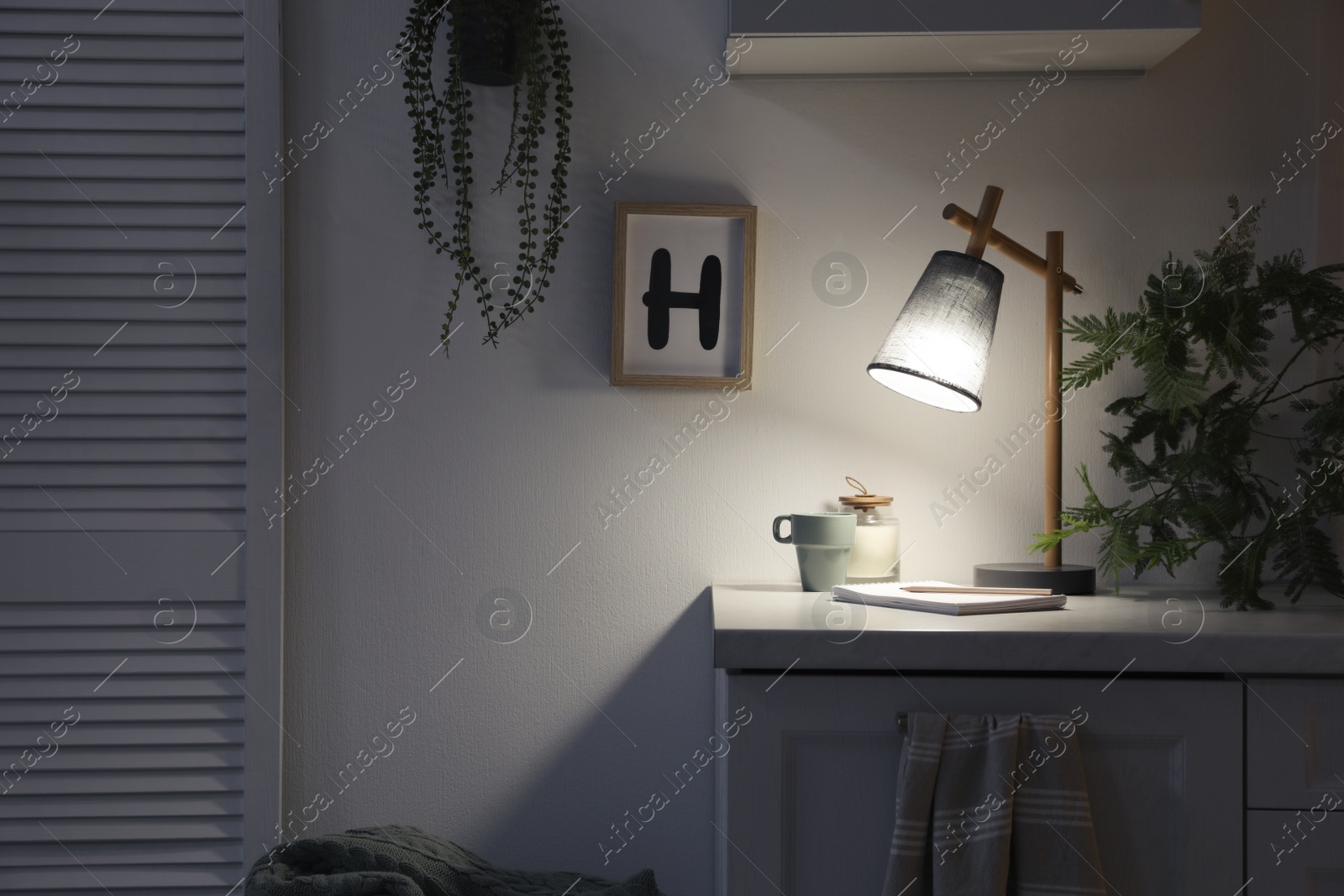 Photo of Stylish lamp and decor on white cabinet in room, space for text. Interior element