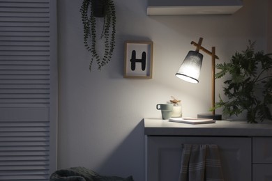 Photo of Stylish lamp and decor on white cabinet in room, space for text. Interior element