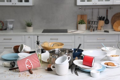 Many dirty utensils, dishware and food leftovers on white table. Mess in kitchen