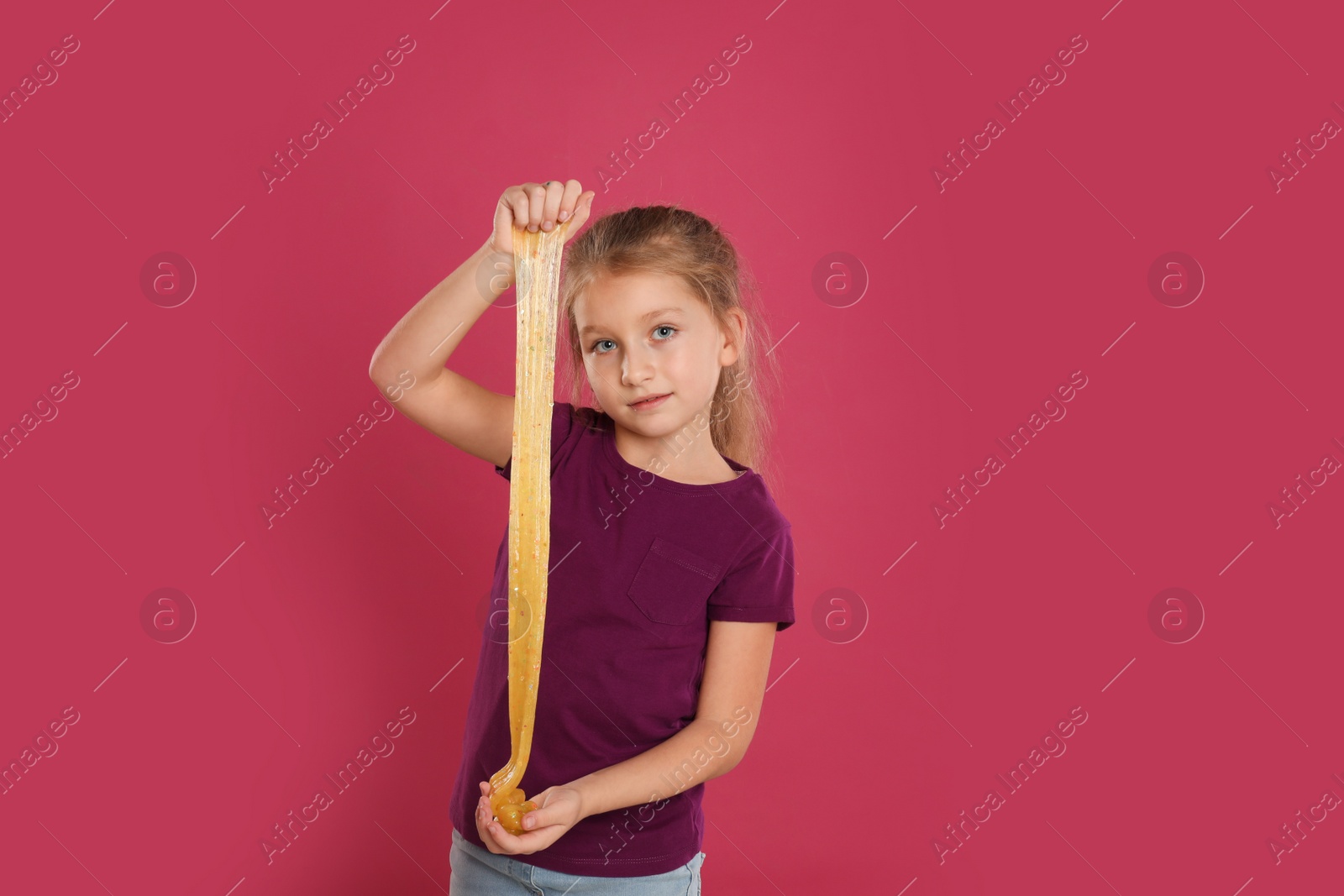 Photo of Little girl with slime on pink background