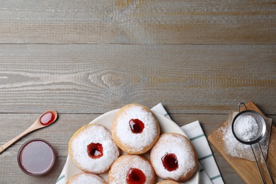 Photo of Hanukkah doughnuts with jelly and sugar powder served on wooden table, flat lay. Space for text