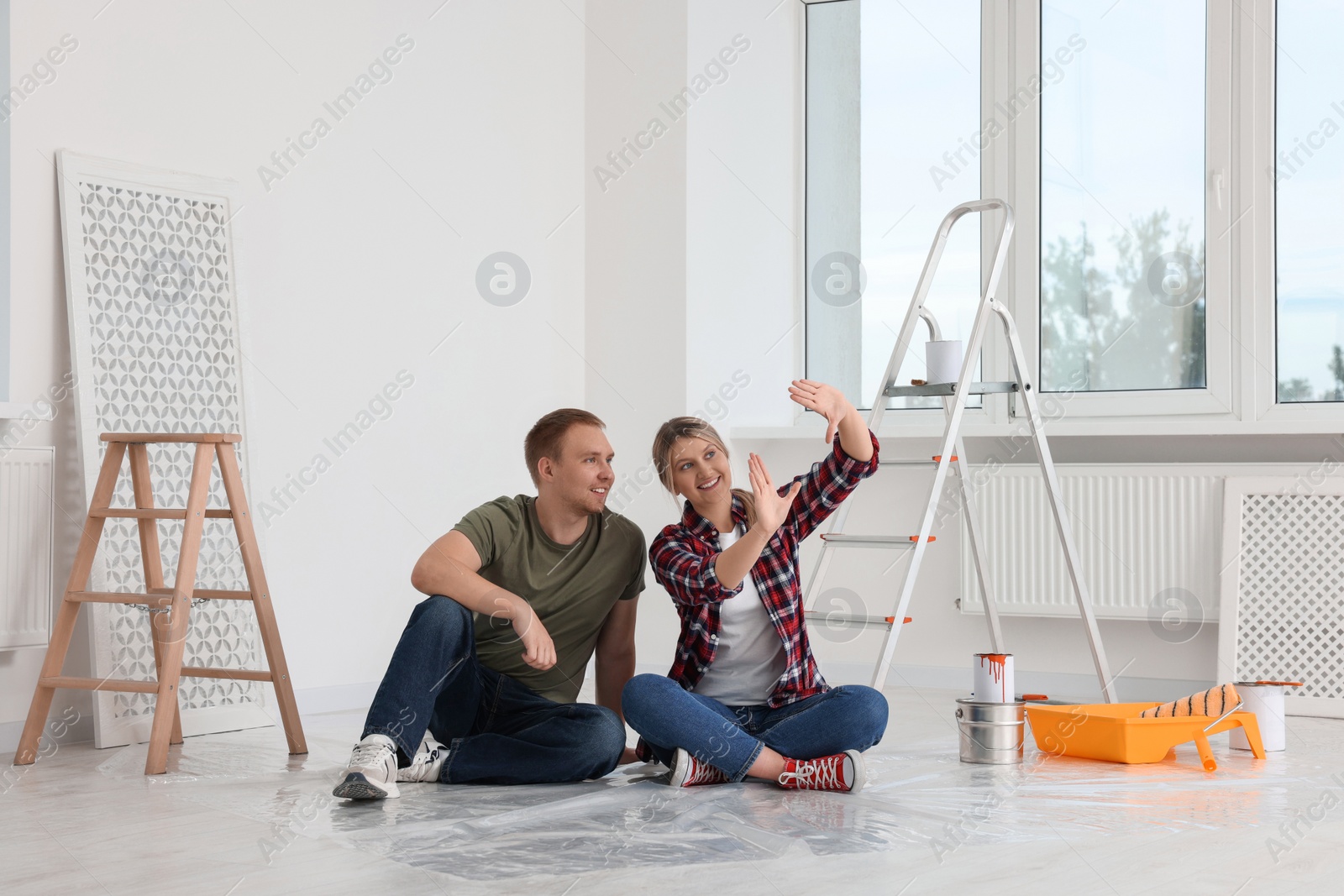 Photo of Happy couple discussing interior details in apartment during repair