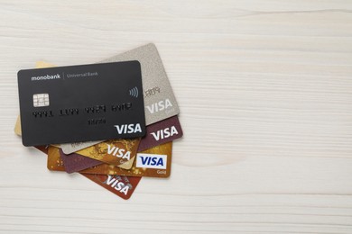 Photo of MYKOLAIV, UKRAINE - FEBRUARY 22, 2022: Visa credit cards on white wooden table, flat lay. Space for text