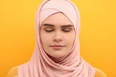 Photo of Portrait of Muslim woman in hijab on orange background