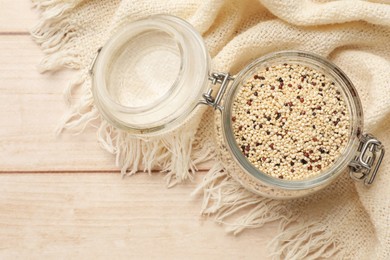 Photo of Raw quinoa seeds in jar on wooden table, top view. Space for text