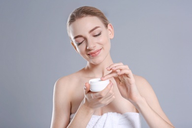 Photo of Young woman with jar of body cream on color background