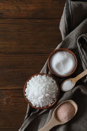 Photo of Different types of organic salt on wooden table, flat lay. Space for text