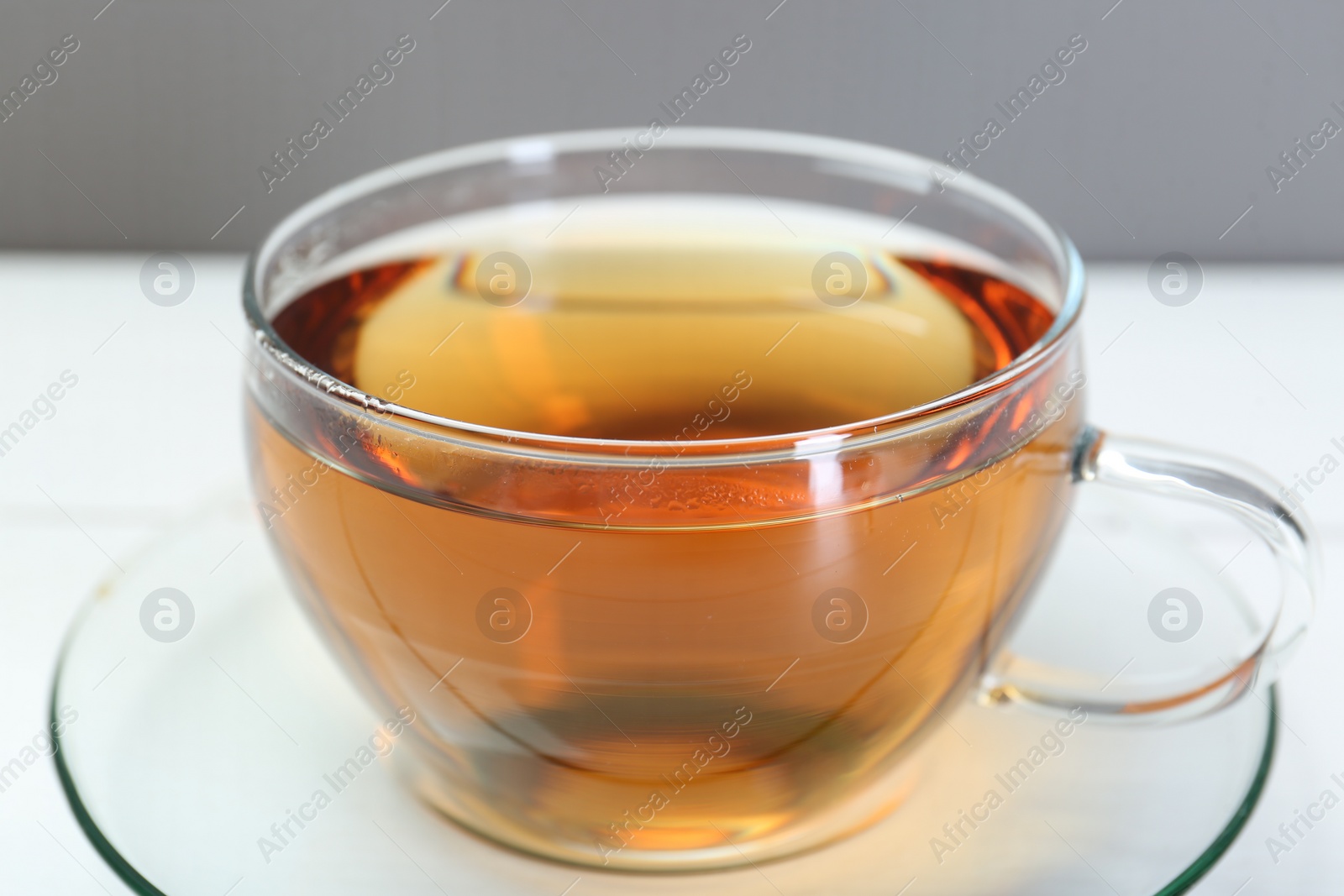 Photo of Glass cup of tea on white table, closeup