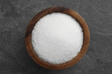 Photo of Granulated sugar in bowl on grey textured table, top view