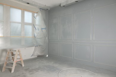 Grey fresh painted wall with frames near window