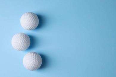 Photo of Three golf balls on light blue background, flat lay. Space for text