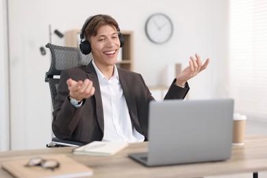 Man in headphones using video chat during webinar at wooden table in office