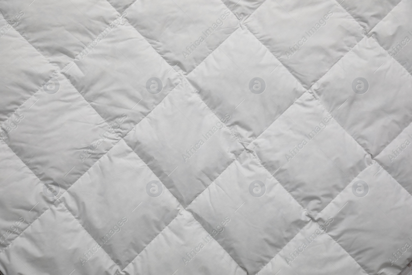 Photo of Soft quilted blanket as background, top view