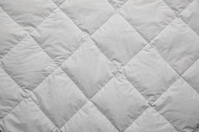 Photo of Soft quilted blanket as background, top view