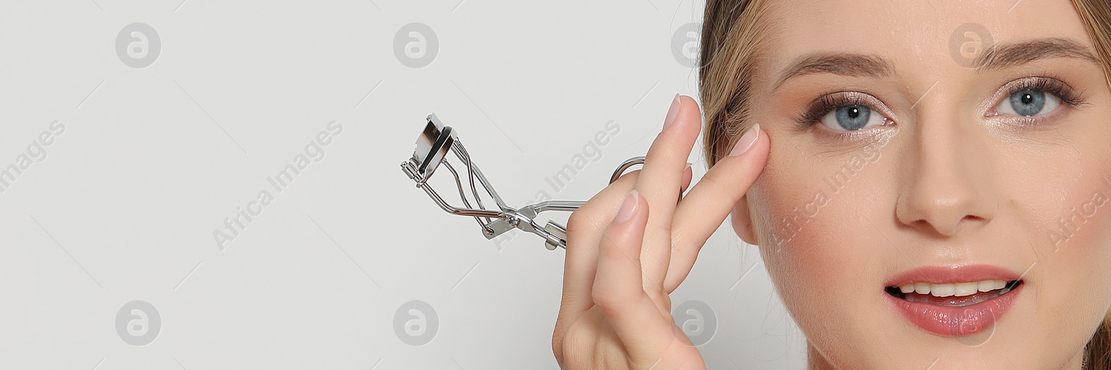 Image of Young woman holding eyelash curler on white background, space for text. Banner design