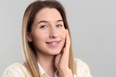 Photo of Portrait of smiling woman with dental braces on grey background