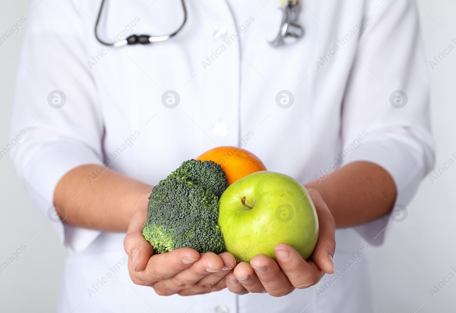 Photo of Female nutritionist with products on light background, closeup