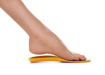 Photo of Woman fitting orthopedic insole on white background, closeup. Foot care
