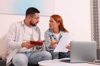 Emotional couple calculating taxes at table in living room