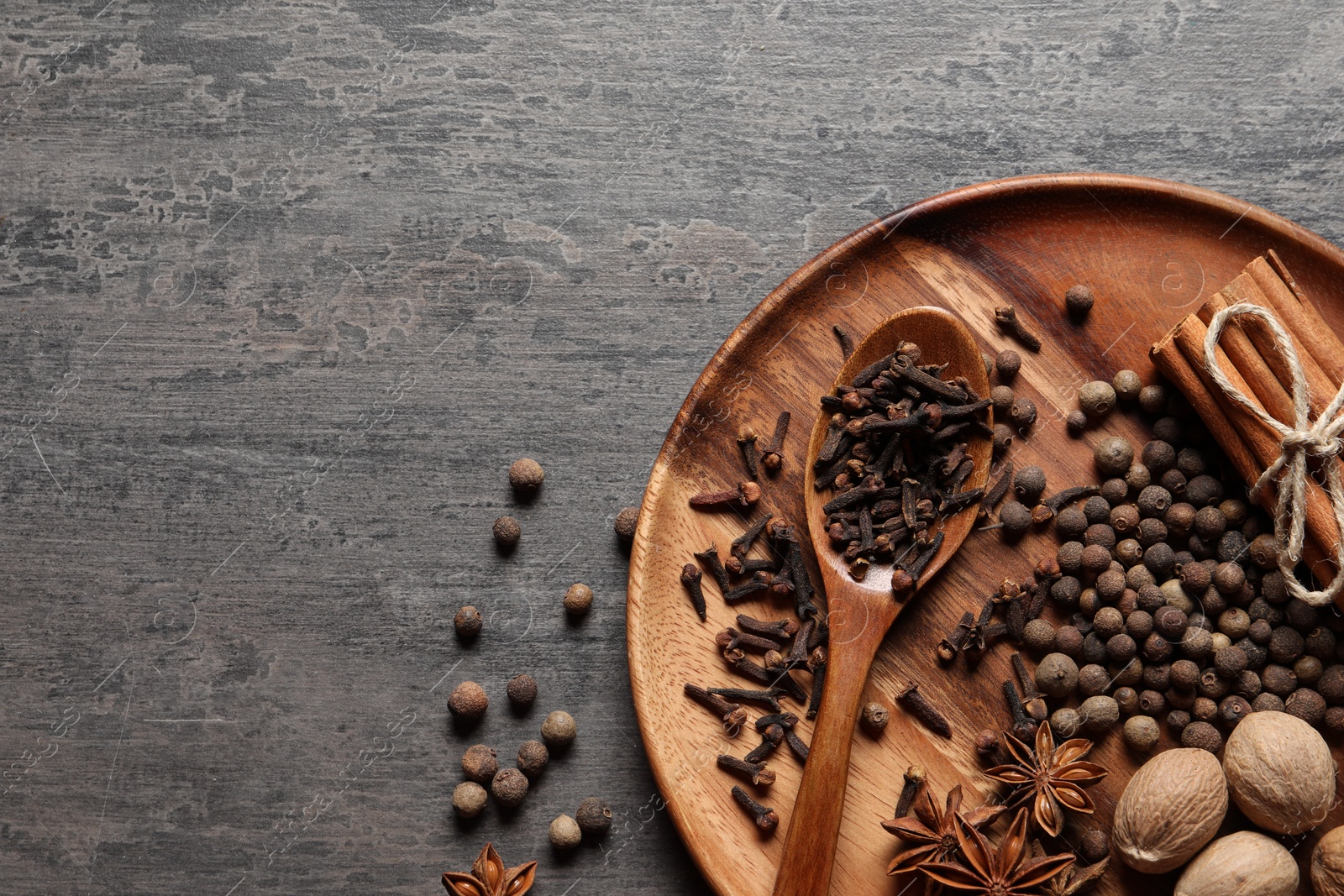 Photo of Different spices and nuts on gray textured table, top view. Space for text