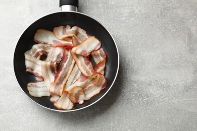 Photo of Delicious bacon slices in frying pan on light grey table, top view. Space for text