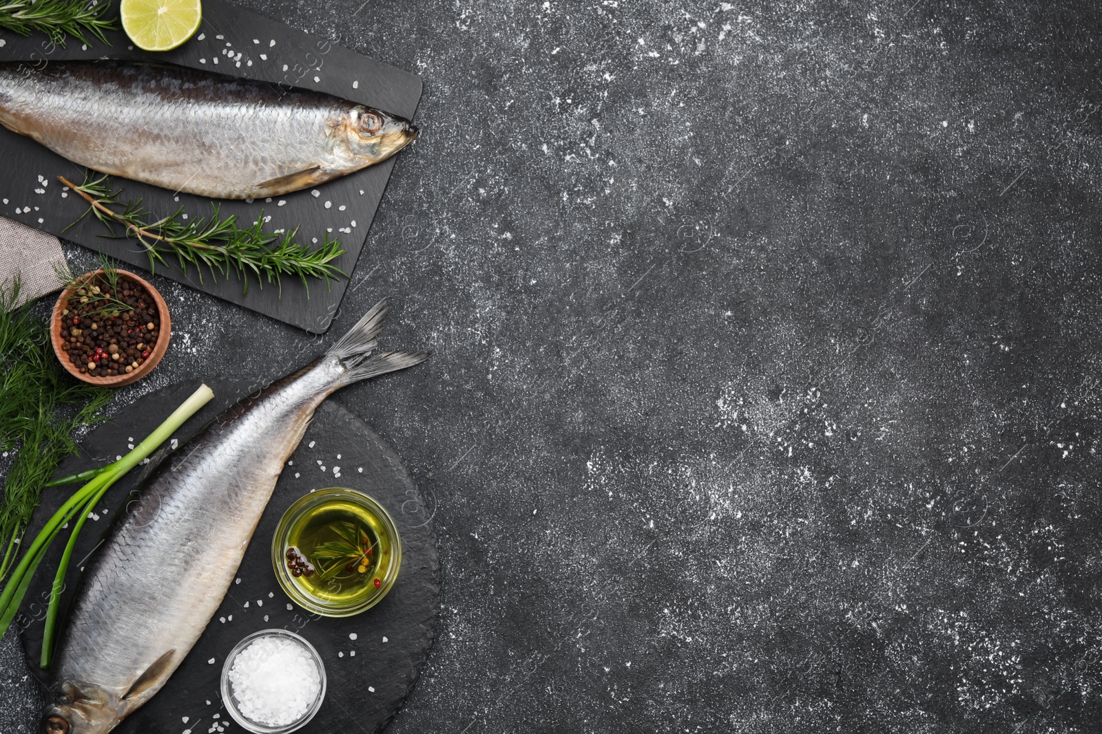 Photo of Delicious salted herrings and ingredients on dark grey table, flat lay. Space for text